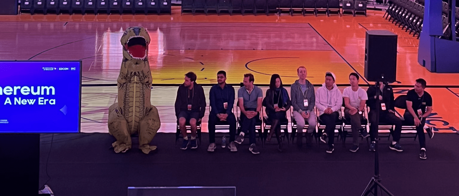Buterin moderating a panel discussion in a green dinosaur costume.