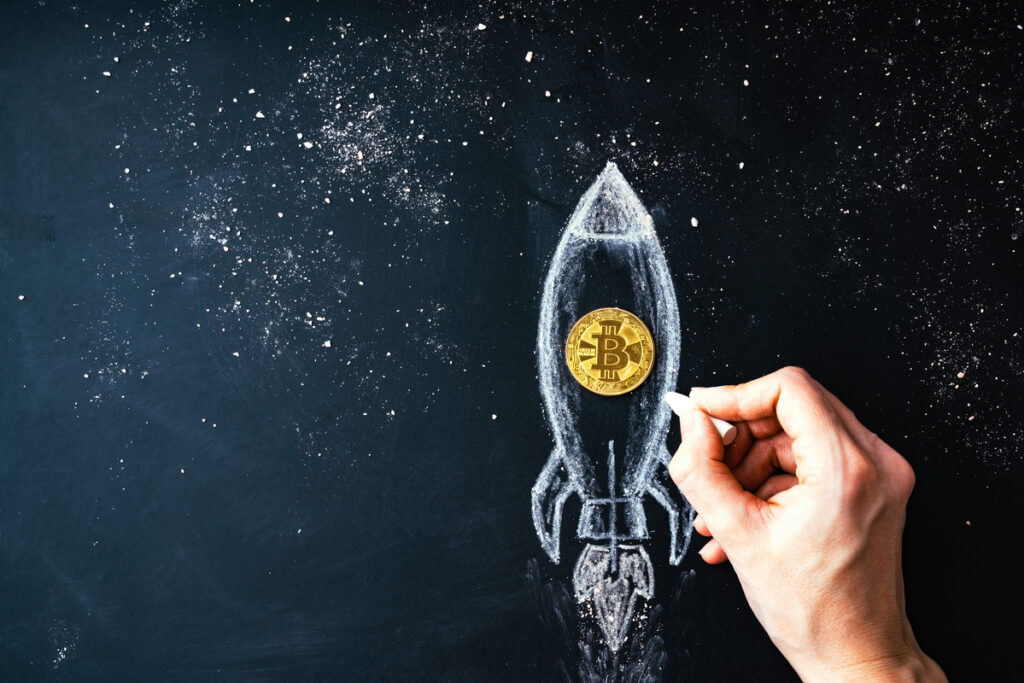 Image showing man drawing rocket around a Bitcoin logo