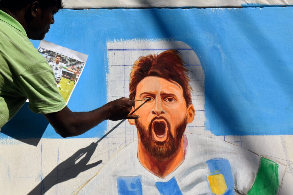 A painter draws an image of Argentina's soccer player Lionel Messi, on a wall along a road ahead of the FIFA World Cup, in Kolkata.