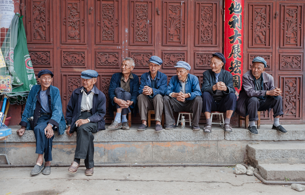 Elderly people sit in front of a social welfare home on July 8, 2013 in Dali, China.In China there is a shortage of elderly care with thousands of applicants on the waiting list.