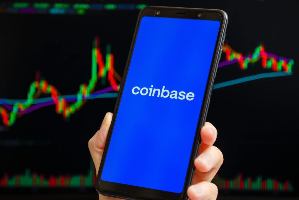 Coinbase mobile app running at smartphone screen with trading candlestick chart at background. Coinbase is American cryptocurrency exchange and trading platform