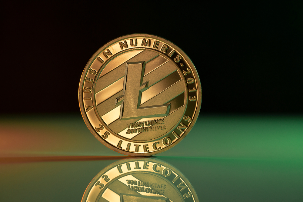 Litecoin LTC cryptocurrency physical coin placed on reflective surface and lit with green and red lights
