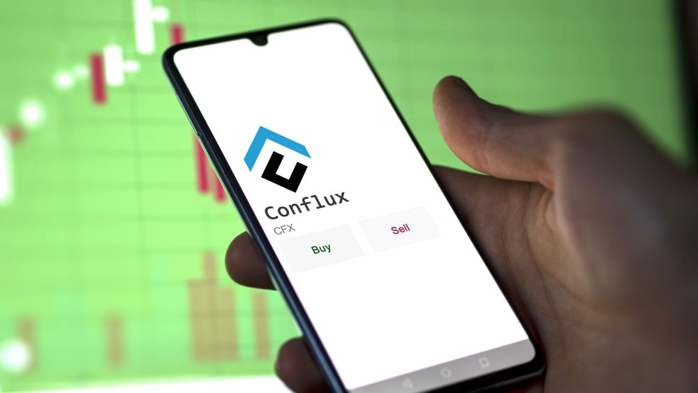 March 11 2023 London UK. An investor's analyzing the Conflux coin on screen. A phone shows the crypto's prices to invest in CFX
