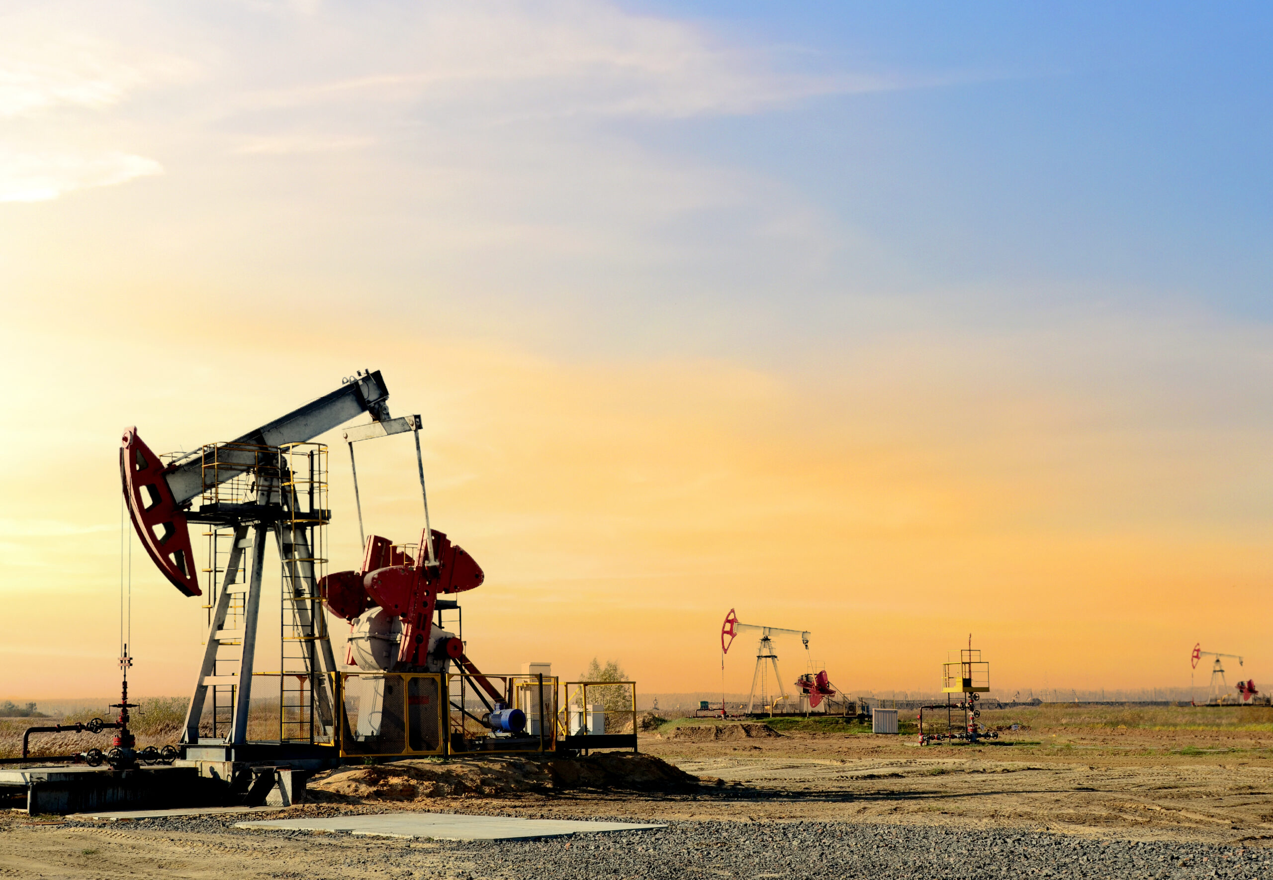 Crude oil pump jack at oilfield on atmospheric sunset backround. Fossil crude output and fuels oil production. Oil drill rig and drilling derrick. Global crude oil Prices, energy, petroleum demand