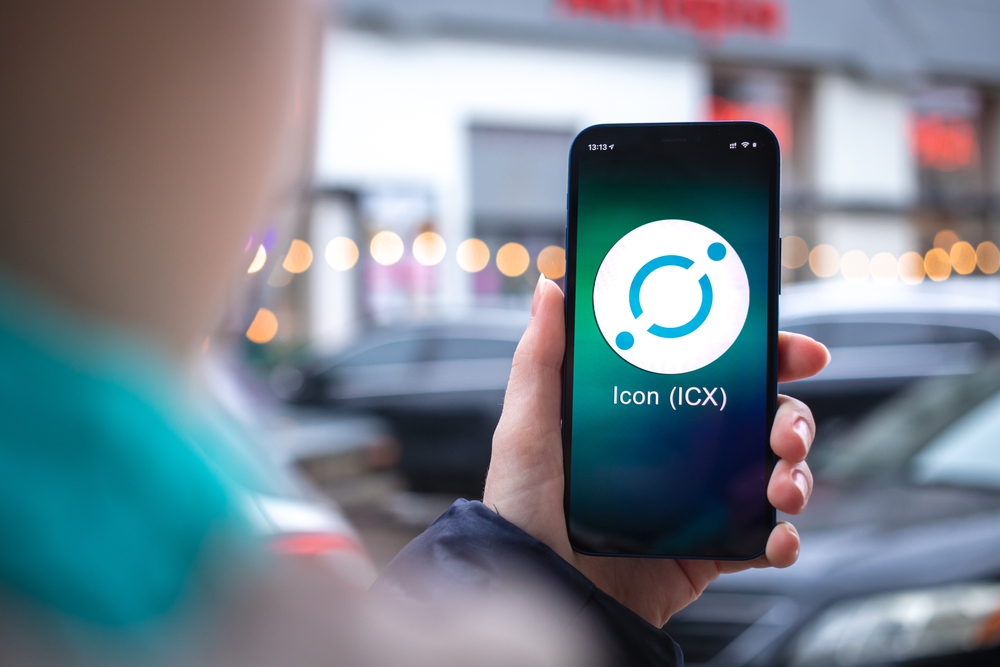 Kharkov, Ukraine - February 2, 2022: Icon ICX coin symbol. Trade with cryptocurrency, digital and virtual money, mobile banking. Hand with smartphone, screen with crypto icon close-up